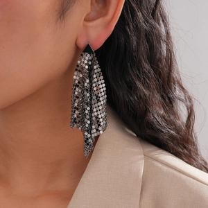 Detail of silver metallic mesh tassel earrings with black triangle geometric studs