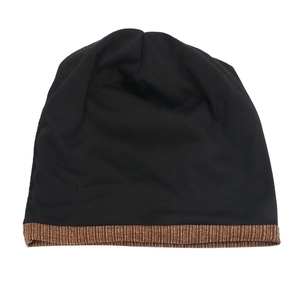 Detail of knit beanie featuring black fabric and contrast brown corduroy brim texture