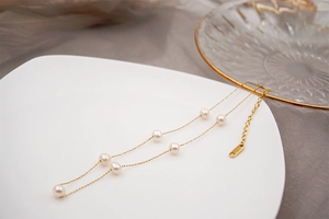 Close-up of double-layer gold chain with freshwater pearls on a white ceramic tray