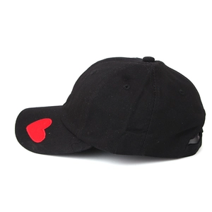Detail of black cotton baseball cap featuring a small red embroidered heart on the side
