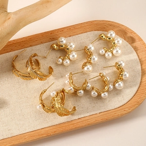 Collection of French-style pearl gold earrings and leaf hoops on a wooden tray