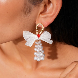 Detail of elegant bow earrings with pearls and red gems on a model's ear