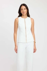 Detail of white sleeveless top with gold hook-and-eye closures and wide-leg trousers