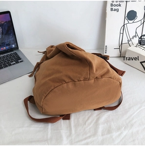 Detailed bottom view of a brown canvas backpack on a white background with books