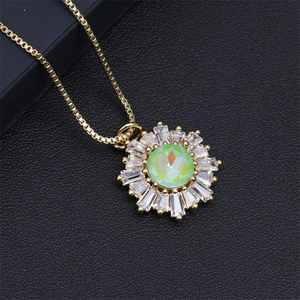 Detailed macro view of gold sunflower pendant with green stone and zircons on black leather