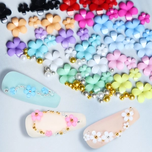 Flat lay of colorful resin 5-petal nail art flowers with gold beads and pearls decoration
