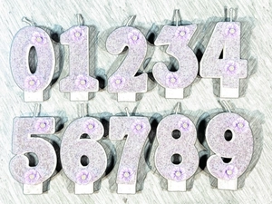Purple glitter number candles 0-9 set for birthday cakes on a grey textured background