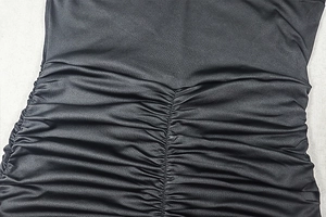 Detail of ruched black fabric showing intricate pleats and elastic texture on a dress