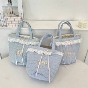 Detail of blue quilted bucket bag with lace trim, heart patches and pink bows