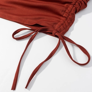 Detail of the side drawstring and ruched ribbed fabric on the dark red mini dress