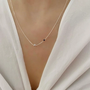 Close-up of 925 sterling silver necklace with iridescent and navy blue beads worn by model