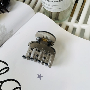 Close-up of a transparent grey shark hair claw clip on an illustrated book page
