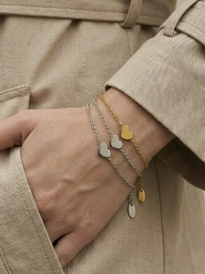 Macro detail of heart charm bracelets featuring K18 gold plating and polished mirror finish
