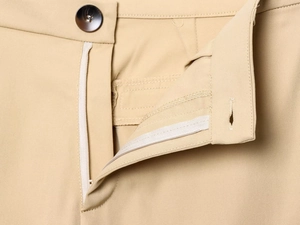 Detail of the khaki trousers showing the resin button and high-quality zipper fly closure