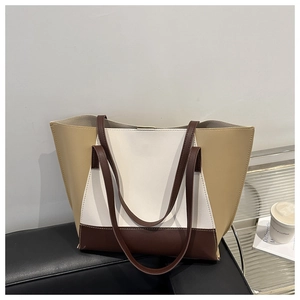Borsa tote tricolore minimalista marrone beige e bianca su una panchina nera in pelle