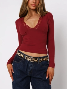 Detail of the V-neckline with delicate eyelash lace trim on a slim burgundy top