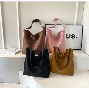 Detailansicht matter Wildleder-Shopper in vier Farben auf minimalistischen weißen Stufen