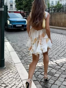 Detail of a white floral backless halter mini dress with layered ruffle hem and open back
