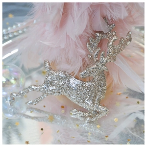 Macro shot of silver reindeer ornament with glitter texture on pink feather background