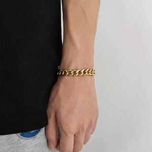 Close-up of 11mm gold stainless steel Cuban link bracelet worn on a male wrist