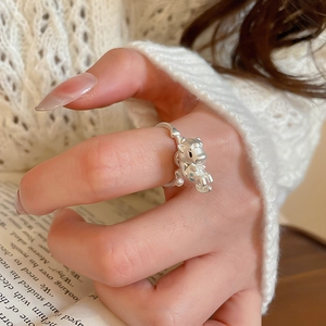 Detailed view of silver bear ring with blue dot detail on a beige knit background