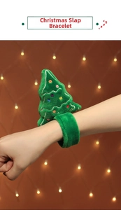 Close-up of green plush Christmas tree slap bracelet on arm with festive bokeh background