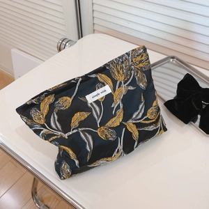 Elegante schwarze Kosmetiktasche mit Gold- und Silberstickerei und gewebtem Etikett
