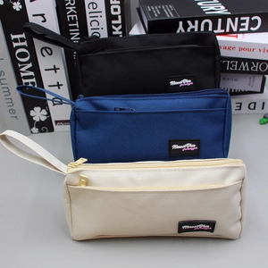Close-up of canvas stationery pouches with dual-layer zippers and hand straps in three colors