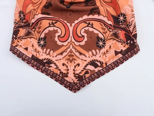 Detail of bohemian orange V-shaped hem and paisley print on chiffon fabric top