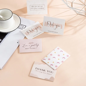 Flat lay of pink and beige minimalist greeting cards with various blessing quotes