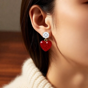 Gros plan d'un mannequin portant des boucles d'oreilles cœur rouge avec zircon