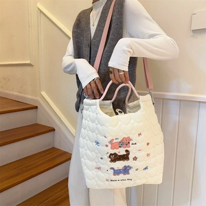 Close-up of white quilted tote bag featuring cute cartoon cat embroidery and pink handles