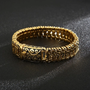 Detail of gold woven link bracelet with embossed floral pattern on the rectangular clasp