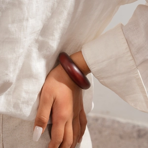 Detail shot of a wide dark red resin cuff bracelet showing minimalist circular design
