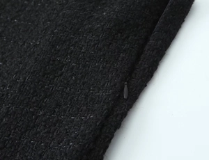 Close-up of invisible zipper detail on black tweed fabric of stylish french mini dress