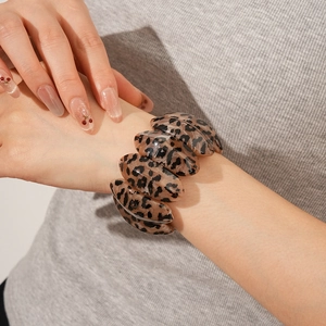 Detail of wide resin bracelet featuring vintage leopard print on a woman's wrist
