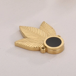 Elegant gold clover leaf pendant with black round gemstone inlay on fabric background