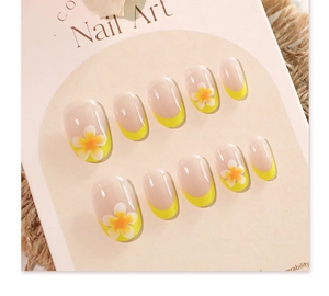 Macro view of French yellow tip press-on nails with white flower patterns on a display card
