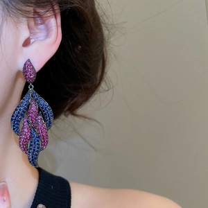 Detailed view of long teardrop earrings with pink and blue zircons on model