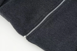 Detail eines hochwertigen Silbermetall-Reißverschlusses an einer dunkelgrauen Wolljacke