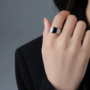 Detail of a wide silver band ring with large black gemstone worn on an index finger