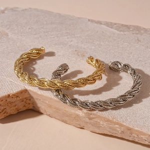 Minimalist twisted metal open cuff bracelets in gold and silver finish on stone