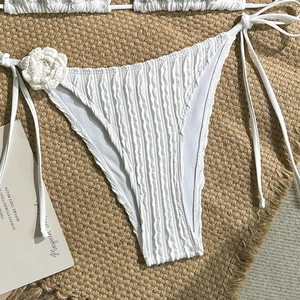 Detailed view of white bikini bottoms with 3D floral accent and ribbed texture