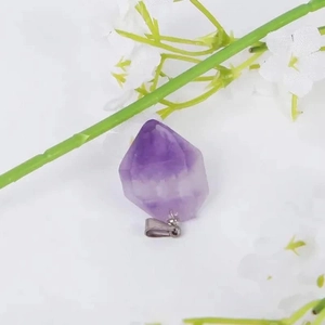 Amethyst crystal pendant with silver clasp on white background with floral accents