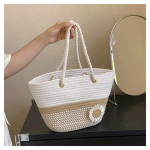 Detail of hand-woven tote bag showing white and beige rope textures with a daisy charm
