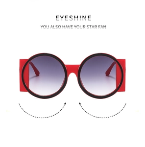 Close-up of oversized red round frame sunglasses with purple gradient lenses and black trim