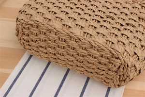 Detailed close-up of woven paper straw handbag base on blue striped fabric background