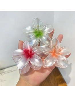 Detailed view of three translucent plumeria flower hair claws with vibrant color gradients