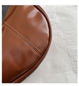 Detail of premium brown leather texture with precise double stitching on shoulder bag