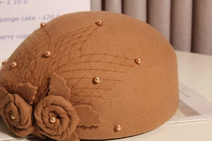 Close-up of brown wool felt beret featuring mesh veil, faux pearls, and floral accents